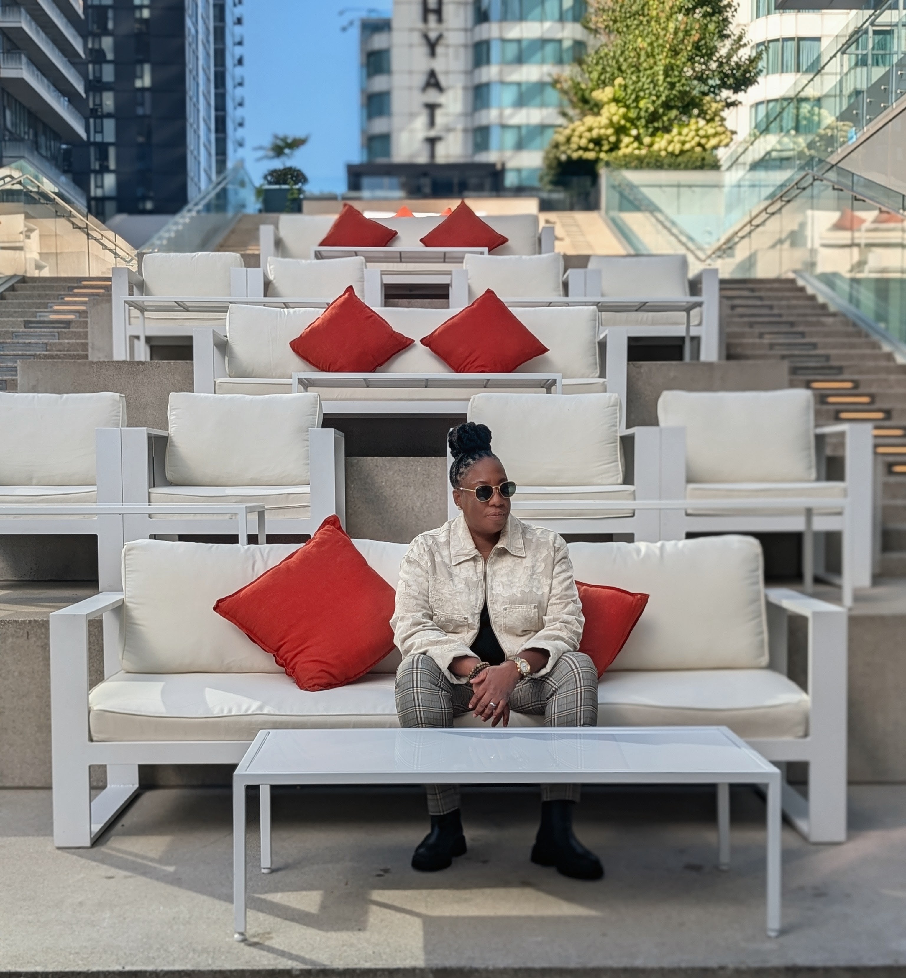 DJ JJ Rock seated on a Toronto terrace in sunglasses and a cream jacket